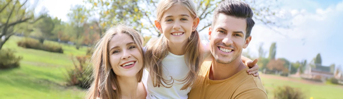 Dentist LaGrange GA Family Dentistry Focused a mother, father, and daughter pose for a family photo while outside in a park