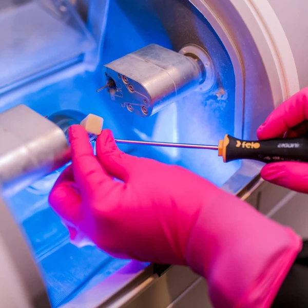 a detailed shot of a dental assistant loading the material needed to create a dental implant into the machine