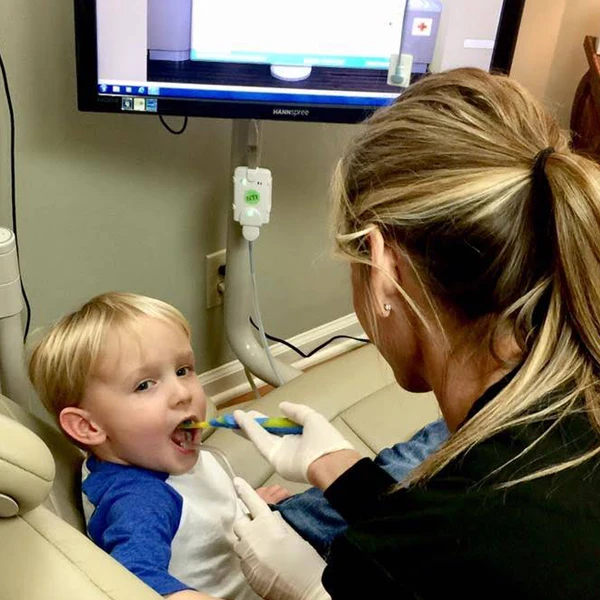 Dentist LaGrange GA Toddler Learning How To Brush Teeth a small boy is getting his teeth brushed by a dental hygienist who is instructing him